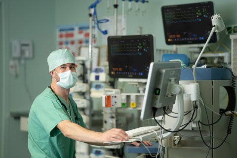 Dr. Jakob Wittenstein (links) in OP-Kleidung an einem Bildschirm.