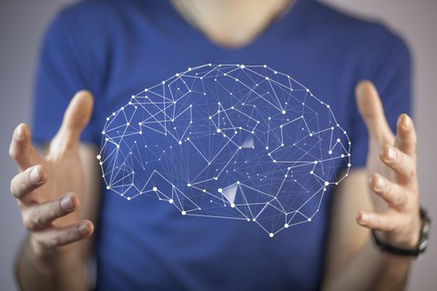 Der Oberkörper einer Person, die mit ihren Händen ein Hologramm eines Gehirnes präsentiert.