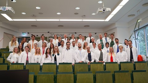 Gruppenfoto der ersten Kohorte des Studiengangs MEDiC zur Abschlussvorlesung im Juli 2025. Die Studierenden tragen alle einen weißen Kittel. 