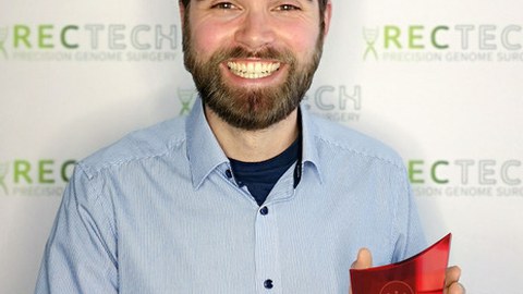 Felix Lansing presenting the Science4Life award, a ca. 25 cm tall trophy made of transparent and red glass
