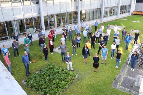 Wissenschaftliche Teilnehmer des Konferenz des SFB 1143 im Jahr 2021 auf einer Wiese, fotografiert von oben.