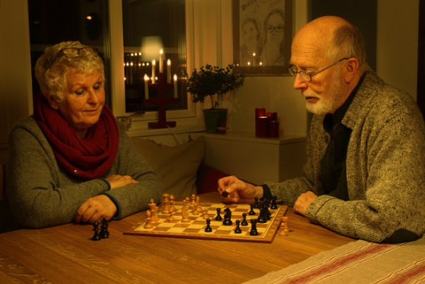 older man and woman play chess