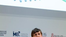 Andre Geim hebt erklärend die Hände. Im HIntergrund die Power Point Präsentation.