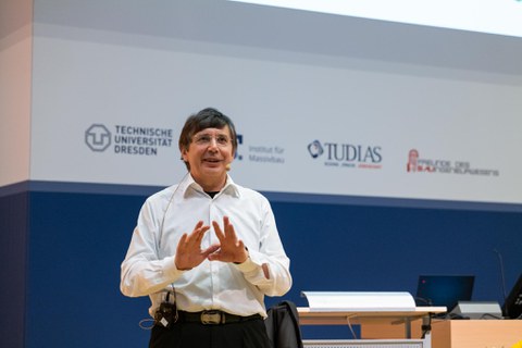 Andre Geim vor einem Banner der TU Dresden.