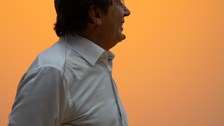 Halbprofil von Andre Geim vor orange beleuchteter Wand.