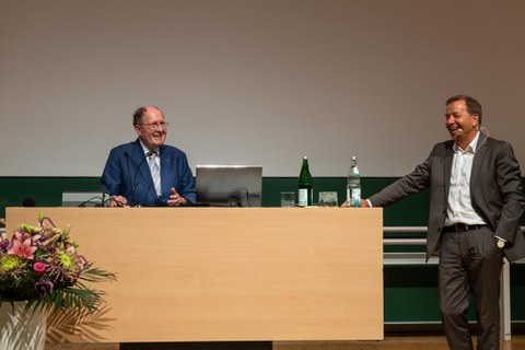Redner am Pult und Mann mit Mikrofon lachen