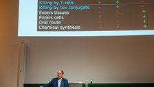 Mann am Pult mit Powerpoint im Hintergrund