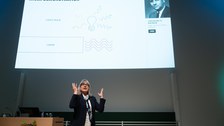 Donna Strickland steht im Hörsaal, im Hintergrund die Präsentation.