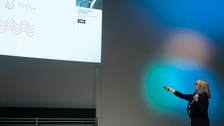 Donna Strickland zeigt mit der Hand auf ihre Präsentation.