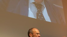 Prof. Dr. Carsten Timm ruft Fragen für Prof. Reinhard Genzel auf, der hinter ihm an die Wand projiziert wird