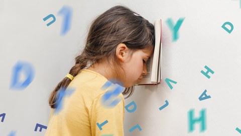 Mädchen lehnt sich mit Buch an die Wand.