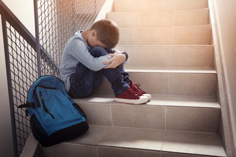 Kind sitzt weinend auf einer Treppe.