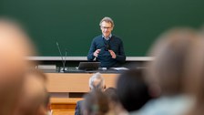 Sprecher steht am Pult