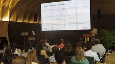 Der Saal ist voller Menschen. Auf der Powerpoint ist jetzt eine Präsentation