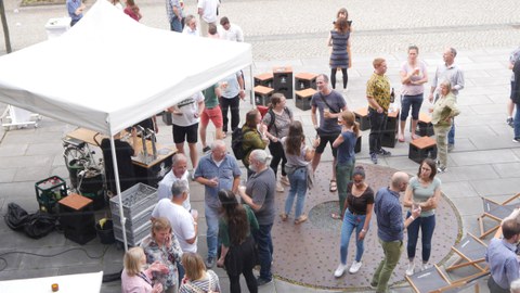 Vor dem Getränke Wagen stehen Menschen und trinken Bier