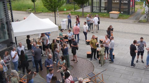 Vor dem Biologie Gebäude stehen Menschen mit Getränken