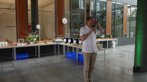 Ein Mann steht mit Mikro vor dem Buffet