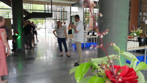 Mann mit Mikro steht vor dem Buffet. Vor ihm steht eine Frau