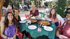 Mehrere Personen sitzen am gedeckten Tisch und lachen in die Kamera.