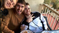 Drei Personen sitzen am Tisch und lachen in die Kamera.