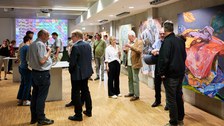 In einer Galerie stehen viele Menschen und unterhalten sich