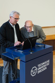 Zwei Männer stehen an einem TU Dresden Pult und schauen in einen Laptop