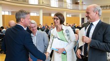 ein Mann schüttelt die Hand einer Frau, die zwischen zwei Männern steht
