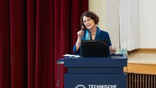 Frau in blauem Blazer steht an dem TU Dresden Pult und spricht zum Publikum