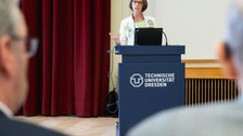 Frau in weißem Blazer steht an einem TU Dresden Pult und spricht zum Publikum