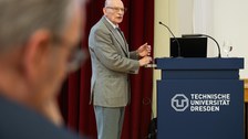 Älterer REdner steht neben dem Pult und doziert