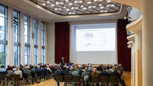 Publikum schaut eine eine Päsentation auf der Leinwamd an