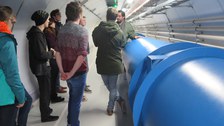 Die Studierenden neben einem Modell des LHC.