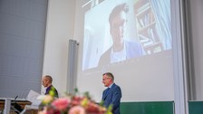 Anschnitt eines Blumenstraußes mit Blick auf zwei Professoren.