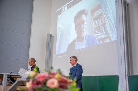 Anschnitt eines Blumenstraußes mit Blick auf zwei Professoren.