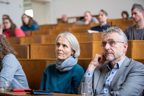Zwei Menschen sitzen im Hörsaal und schauen nach vorn.