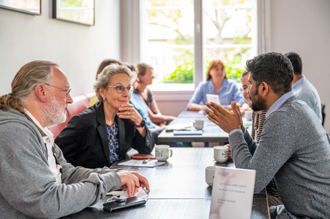 Rektorin im lockeren Gespräch mit Mitarbeitern, am Tisch sitzend