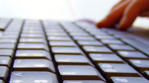 Das Foto zeigt eine Nahaufnahme einer Laptoptastatur, sowie die Hand einer Person, welche den Laptop bedient.