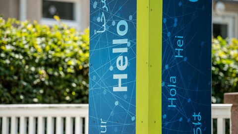 Photo of a blue column with the inscription Hello, Hola and Hei and other languages