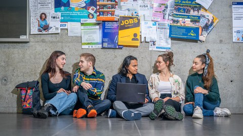 Bild von fünf Studierende, die zusammen auf dem Boden in einem TU-Gebäude sitzen und zusammen lernen.