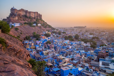view from a mountain range with a castle towards a city of blue houses