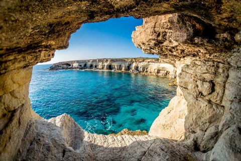 view from the mouth of a cave, looking at clear blue sea and rocks