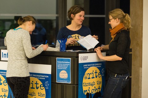 Zwei junge Frauenstehen am Informationstresen und lassen sich zur Langen Nacht des Schreibens beraten.