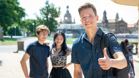 Drei Studenten schauen in die Kamera. Im Hintergrund ist die Dresdner Skyline zu sehen
