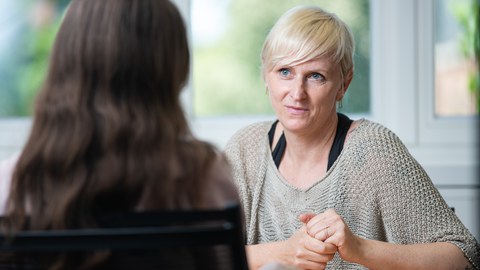 Man sieht eine Frau, die ihrem Gegenüber aufmerksam zuhört.