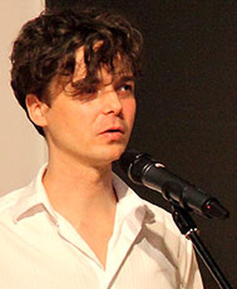 The photo shows André Eckardt standing before a microphone.