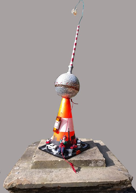 The photo shows an artistic graduation motarboard made out of an orange traffic cone.