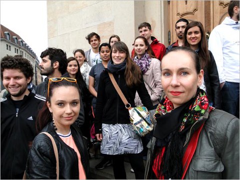 The photo shows a group of people, including Maria Völzer, standing in front of a building.