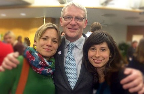 Das Foto zeigt zwei Frauen. Zwischen ihnen steht ein Mann, der die Hände auf die Schultern der Frauen gelegt hat.