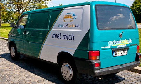 Das Foto zeigt einen grünen VW T4 Bus. Darauf befindet sich das Logo von "Carl und Carla" und der Spruch "miet mich".