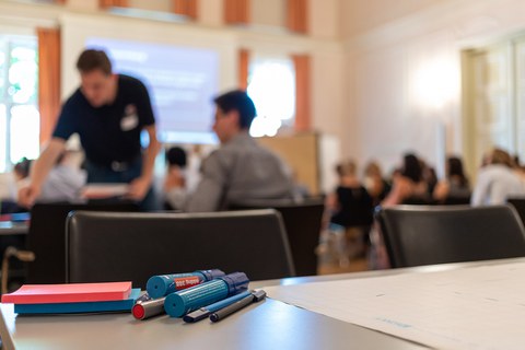 Blick über einen Workshoptisch in den Saal
